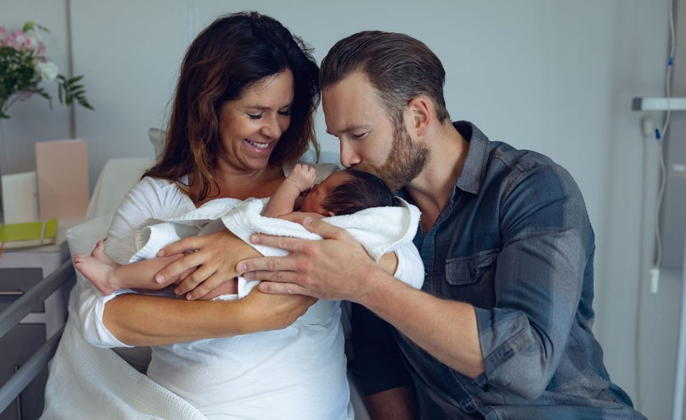 Front view of Caucasian couple holding their newborn baby in the ward at hospital