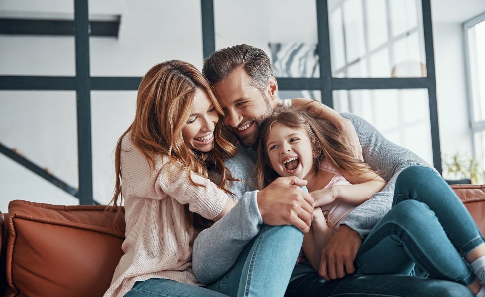 Happy young family smiling and embracing while bonding together at home